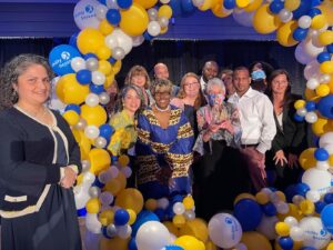 agency team members smiling around balloon arch
