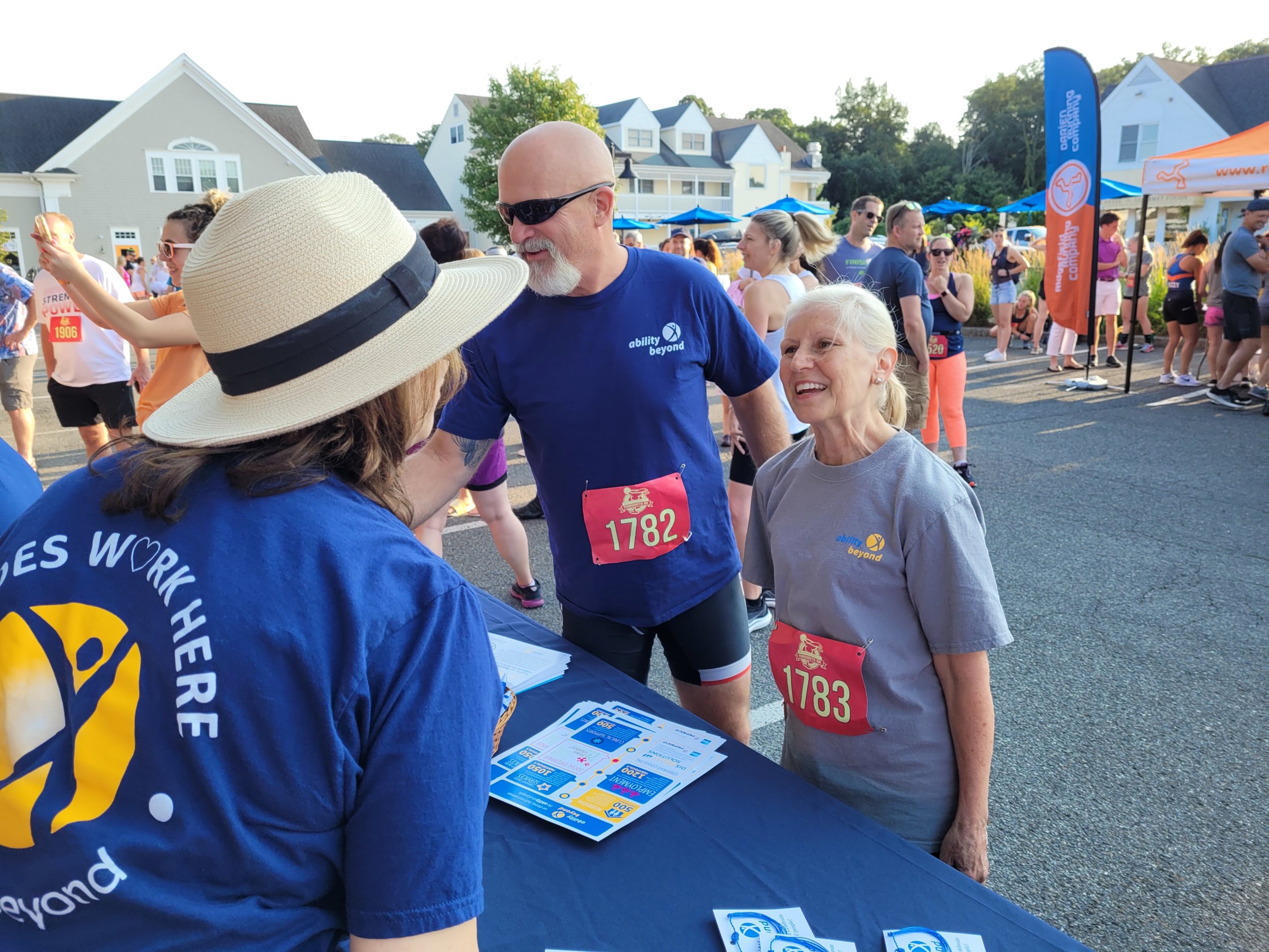 man and woman in race gear talking to Ability Beyond staff before the race